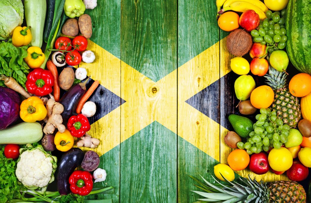Colorful arrangement of tropical fruits  and vegetables on a wooden table, painted with the Jamaican flag. 